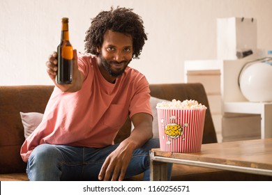 Young African Man Watching A Movie Holding A Popcorn Bucket And Drinking A Beer.