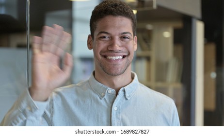 Young African Man Waving And Smiling At Camera