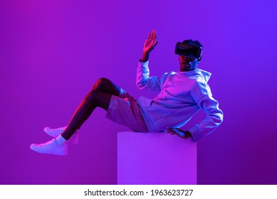 Young African Man Wearing VR Glass Headset In Futuristic Purple Cyberpunk Neon Light Background