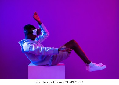 Young African Man Wearing VR Glass Headset On Futuristic Purple Cyberpunk Neon Light Background