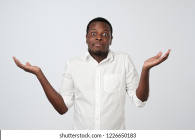 Young African Man In White Shirt Being At A Loss, Showing Helpless Gesture With Arm And Hands, As If He Does Not Know What To Do. Why Did I Fail My Job.