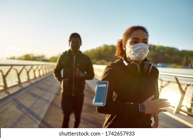 Young african man and woman in medical masks running on the bridge during a pandemic. Sport and coronavirus. Covid-19. Protection. Health concept. Couple jogging. Social distancing - Powered by Shutterstock