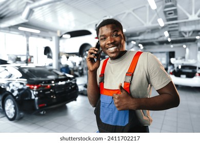 Young African mechanic man wearing uniform using mobile phone in a car service - Powered by Shutterstock