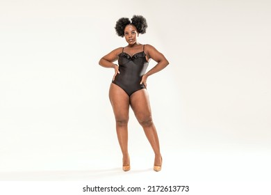 Young African Plus Size Woman Posing In Black One Piece Swimwear, Standing Over Light Grey Studio Background. Copy Space. Full Length Photo. 
