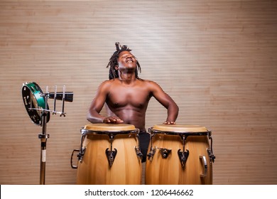 young african rastafarian man enjoys rehearsing and plays the conga, tambourine and cowbell