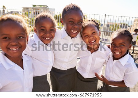 Young African schoolgirls in playground smiling to camera