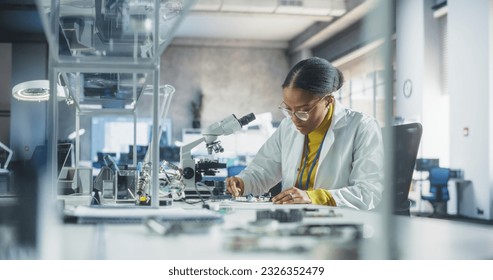 Young African Science Student Conducting Electronics Experiment in a University Workshop. Diverse Black Scholar Using Microscope, Working on Connecting and Testing a Circuit Board in a Laboratory - Powered by Shutterstock