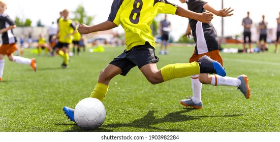 Young African Soccer Player Running Fast And Kicking White Football Ball. Youth Footballers Compete In Tournament Match. Soccer Athlete Kicking Ball. School Sports Competition