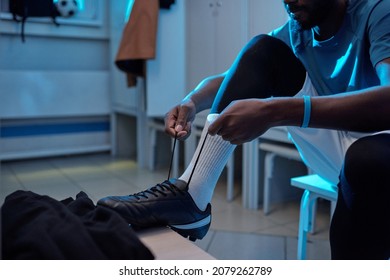 Young African soccer player tying shoelaces while sitting in changing room and getting ready for match or training - Powered by Shutterstock