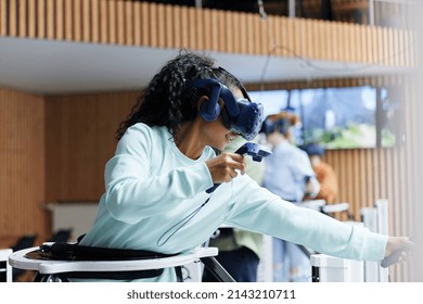 Young African teenage girl wearing a headset and using controllers to explore a digital world at a vr club - Powered by Shutterstock