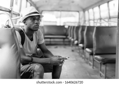 Young African tourist man using mobile phone and riding the bus - Powered by Shutterstock