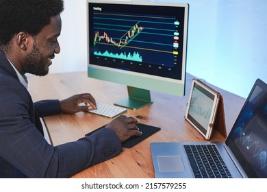Young african trader man using laptop, computer and tablet while working from home - Business and finance concept