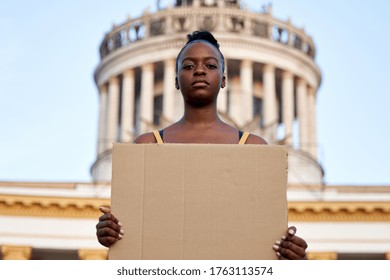 Young african woman activist stand outdoor hold empty blank sign protesting on street. Black female protest against discrimination racism for empowerment, civil rights, racial equality justice concept
