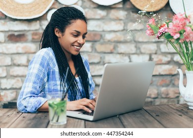 Young african woman at cafe drinking lemonade and working on laptop
 - Powered by Shutterstock