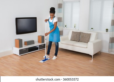 Young African Woman Cleaning Living Room With Mop