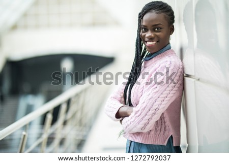 Young african woman with crossed hands standing in office hall