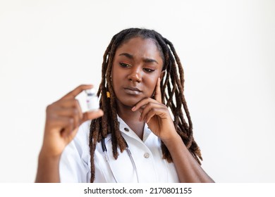 Young African Woman Doctor Is On A Gray Background. Holding Revolutionary Medicine In Hand