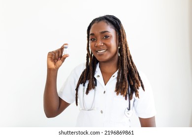 Young African Woman Doctor Is On A Gray Background. Holding Revolutionary Medicine In Hand