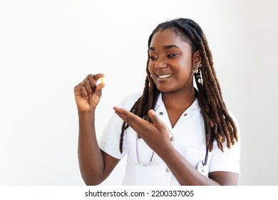 Young African Woman Doctor Is On A Gray Background. Holding Revolutionary Medicine In Hand