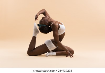 Young African woman doing yoga in stretching position - Shutterstock ID 264939275