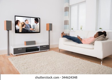 Young African Woman Falling Asleep While Watching Television At Home