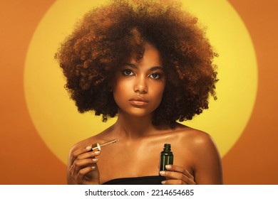 Young African Woman Holding Bottle Of Serum With Dropper Like A Part Of Her Skin Care Routine