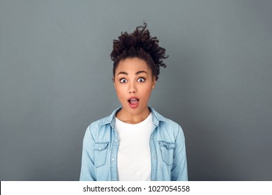 Young african woman isolated on grey wall studio casual daily lifestyle surprised