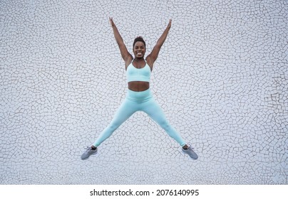 Young african woman jumping in the city with white background - Powered by Shutterstock