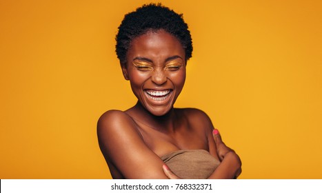 Young african woman laughing against yellow background. Cheerful female model with vivid makeup.