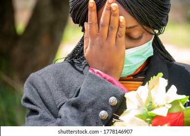 Young African Woman Mourning, Wearing Black And Holding Flowers