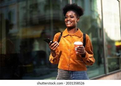 Young african woman outdoors. Beautiful woman with curly hair drinking coffee while walking around town	 - Powered by Shutterstock