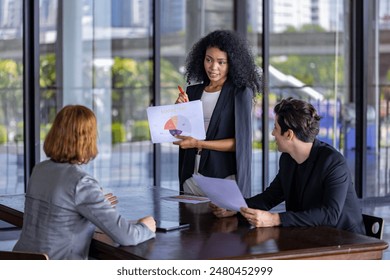 Young African woman sale manager is showing annual report chart to her colleagues in the executive meeting for next year plan with market share pie chart for global business and investment - Powered by Shutterstock