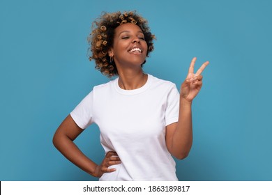 Young African Woman Showing Two Fingers, Positive Or Peace Gesture, On Blue Wall.