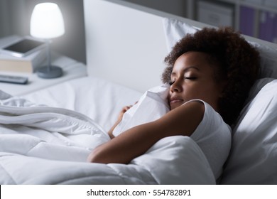 Young african woman sleeping in her bed at night, she is resting with eyes closed