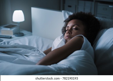 Young african woman sleeping in her bed at night, she is resting with eyes closed