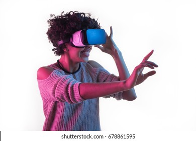 Young African Woman Smiling And Touching Air While Having VR Experience And Adjusting Goggles Isolated On White.