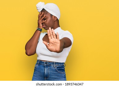 Young African Woman With Turban Wearing Hair Turban Over Isolated Background Covering Eyes With Hands And Doing Stop Gesture With Sad And Fear Expression. Embarrassed And Negative Concept. 