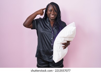 Young African Woman Wearing Pijama Hugging Pillow Smiling Pointing To Head With One Finger, Great Idea Or Thought, Good Memory 