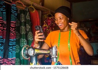 young african woman who is a tailor feeling excited and happy and jubilant while viewing content on her mobile phone