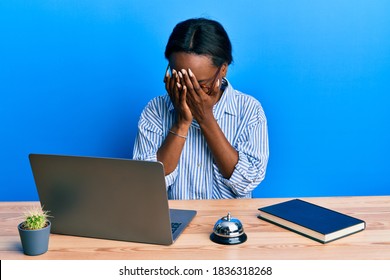 Young African Woman Working At Hotel Reception Using Laptop With Sad Expression Covering Face With Hands While Crying. Depression Concept. 