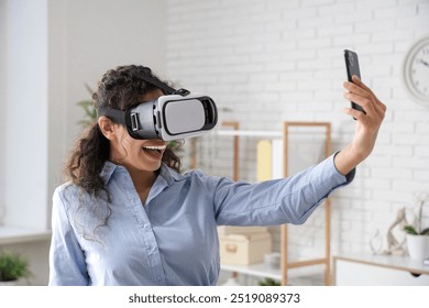 Young African-American businesswoman in VR glasses taking selfie in office - Powered by Shutterstock