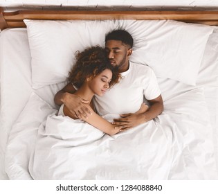Young african-american couple sleeping together in bed, top view, copy space