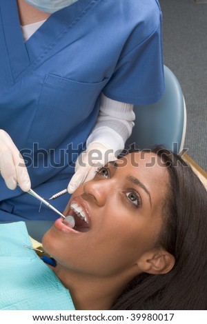 Young African-American ethnic black female opening her mouth while dentist in white latex gloves check condition of her teeth
