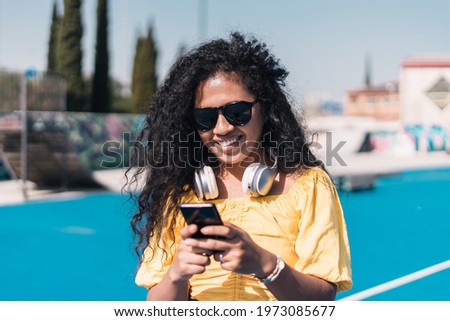 Young African-American girl smiling while texting with her cell phone.