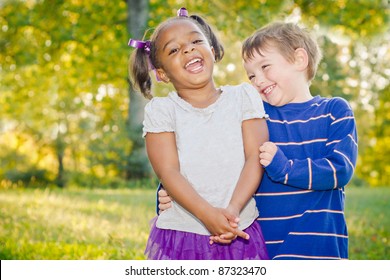 Young African-American girl and young white boy playing together in park