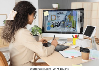 Young African-American graphic designer working with tablet at table in office - Powered by Shutterstock