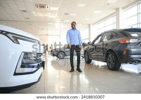 young africanamerican man came to see automobiles in dealership or cars showroom.