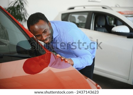 young africanamerican man came to see automobiles in dealership or cars showroom.