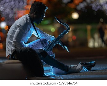 A Young African-American Man With A Saxaphone In A Night City Street