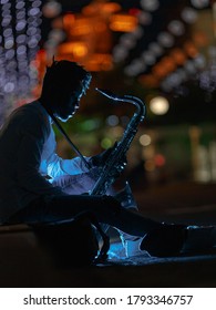 A Young African-American Man With A Saxaphone In A Night City Street